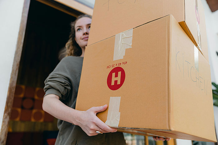 Woman holding moving boxes, symbolizing decades of relocating for husband's career and refusal to move again.