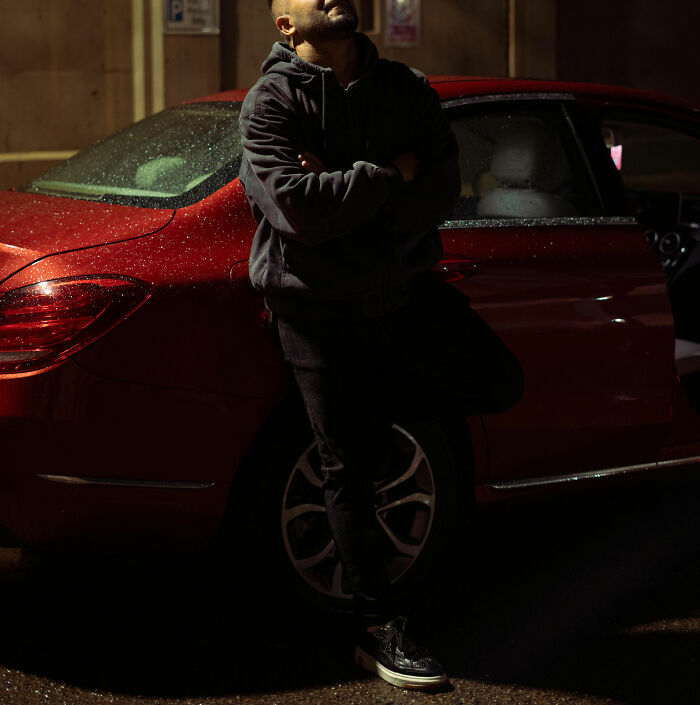 Man leaning against a red car at night, reflecting the vibe of crazy party stories in nightclubs and late-night scenes.