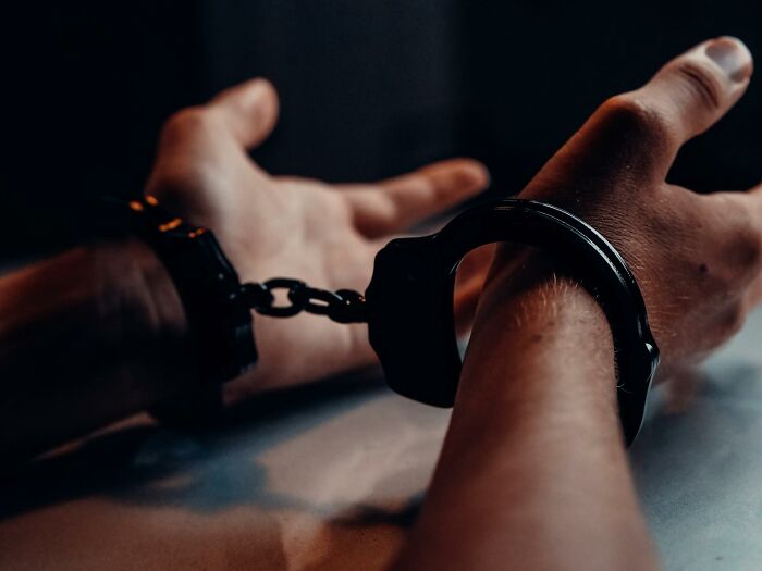 Hands in black handcuffs resting on a table symbolizing progress and hope in America beyond negative headlines.