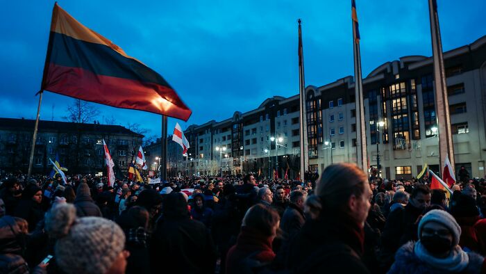 Crowd gathered outdoors at dusk with various national flags representing lesser-known facts about these countries.