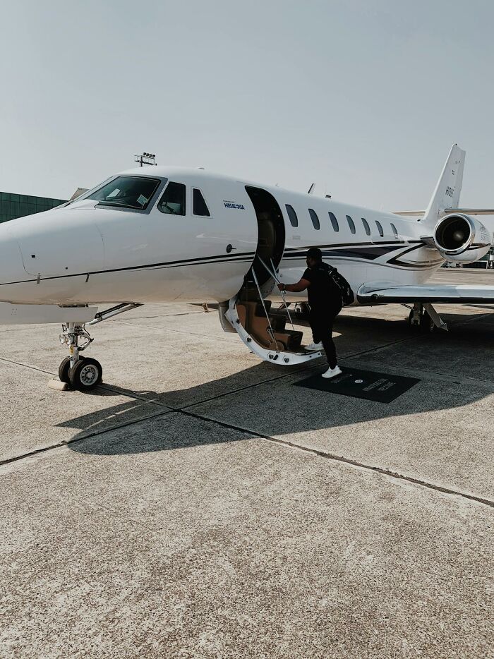 Private jet on tarmac with person boarding, illustrating rich people far from reality and luxury travel lifestyle.