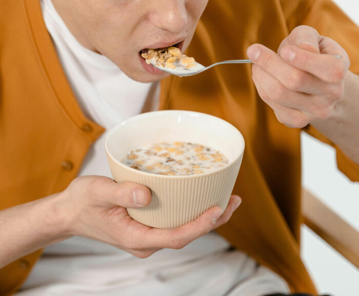 Person eating cereal from a bowl with a spoon, illustrating a casual moment unrelated to crazy party stories or nightclubs.