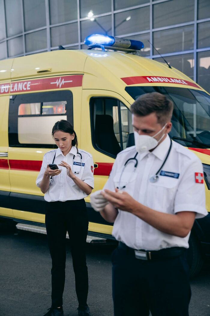Two paramedics by an ambulance, one using a phone, illustrating accidental texts that caused panic situations.