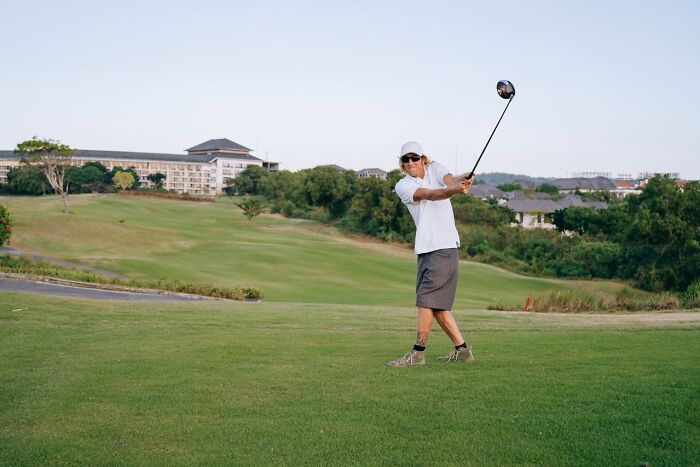 Man playing golf on a lush course, illustrating rich people far from reality with luxury leisure and lifestyle.