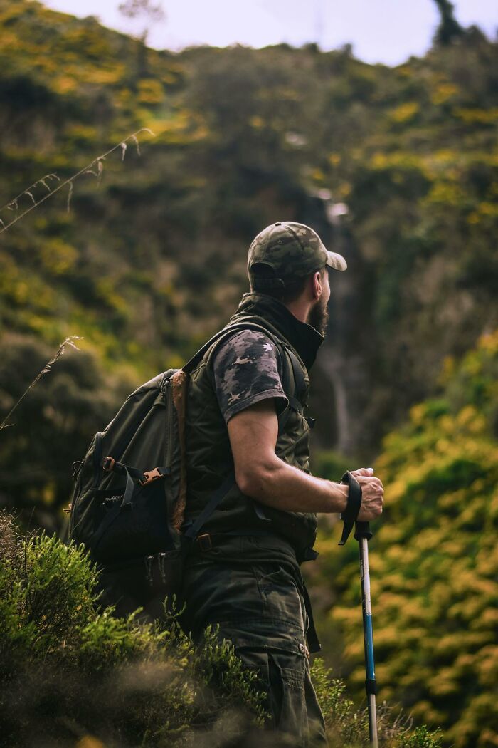 Hiker with backpack and trekking pole in green hillside, creepiest displays of intelligence