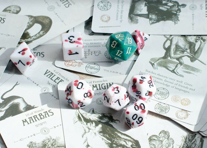 Assorted polyhedral dice on white illustrated tarot-style cards exploring misconceptions about life in prison and hidden truths.