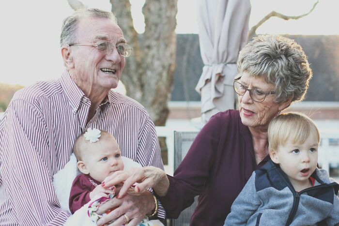 Elderly grandparents with two young grandchildren sharing a moment, illustrating family secrets and bonding.