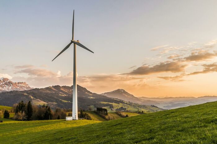 Wind turbine in a green landscape at sunset representing uplifting stories of progress and hope in America.