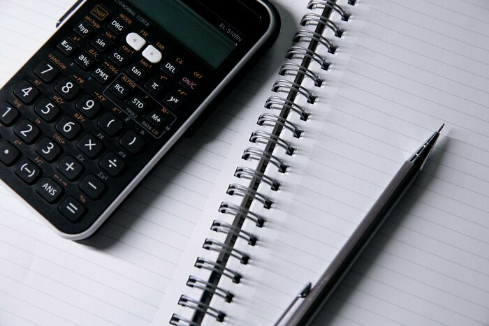 Calculator and pen resting on an open spiral notebook, symbolizing a primary school math quiz challenge. Calculator and pen resting on an open spiral notebook, symbolizing a primary school math quiz challenge.