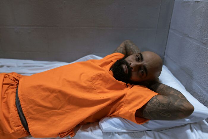 Man in an orange prison uniform lying on a bed, illustrating shocking truths and misconceptions about life in prison.