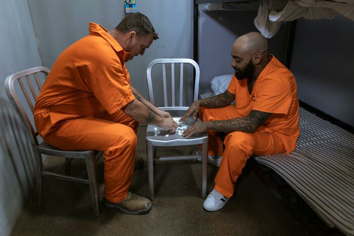 Two inmates in orange prison uniforms playing a game inside a cell, illustrating life in prison misconceptions.