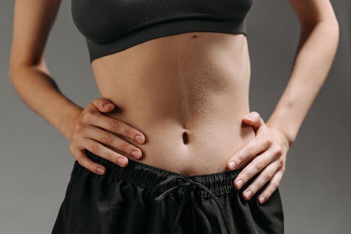 Close-up of a person’s toned abdomen and hands on hips, highlighting physical fitness during night shift chaos.