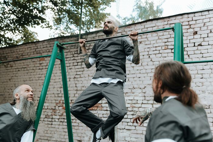 Prison inmates in uniforms exercising on outdoor bars revealing truths about life in prison misconceptions.