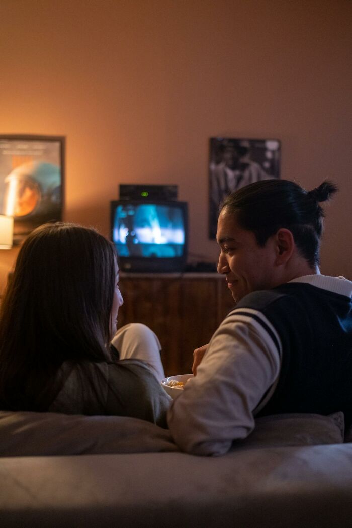 Couple on couch watching TV in dim living room, popcorn and cozy vibe, illustrating creepiest displays of intelligence