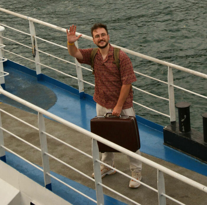 Man waving on ferry deck with suitcase by the water, image for rained frogs story