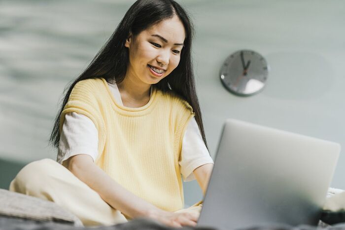 Young woman smiling at laptop, wearing braces and yellow top in a room — creepiest displays of intelligence