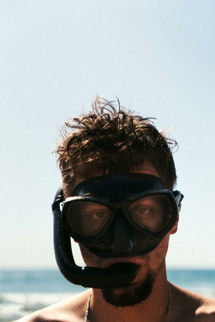 Man wearing a black snorkel mask at the beach, symbolizing 3 AM chaos and night shift work challenges.