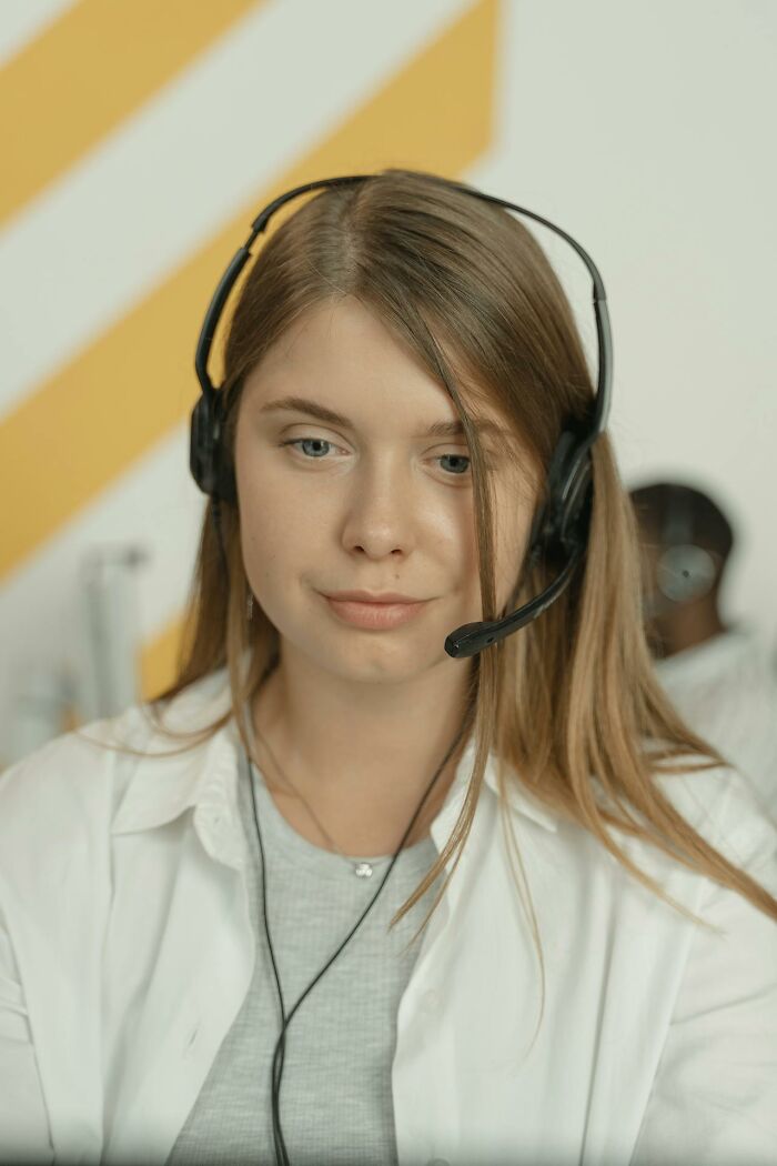 Young woman wearing a headset working night shift in a call center handling 3 AM chaos and difficult customer stories.