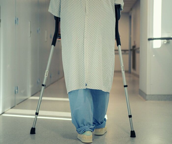 Patient in hospital gown using crutches in corridor, photo for rained frogs anecdote