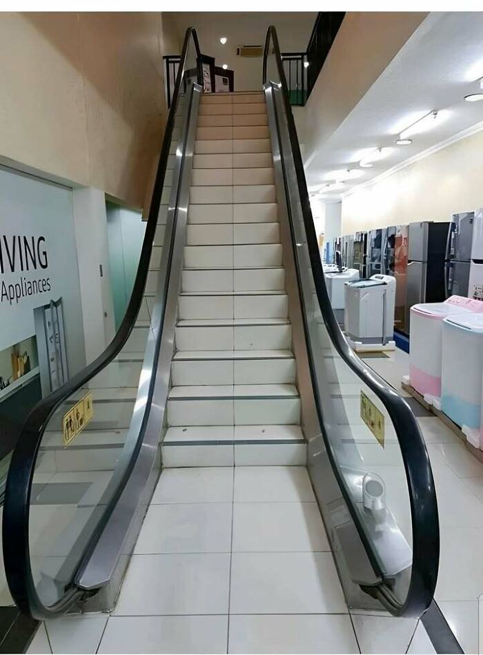 Escalator with missing moving steps replaced by fixed stairs in an appliance store, showcasing a funny Eastern European experience.