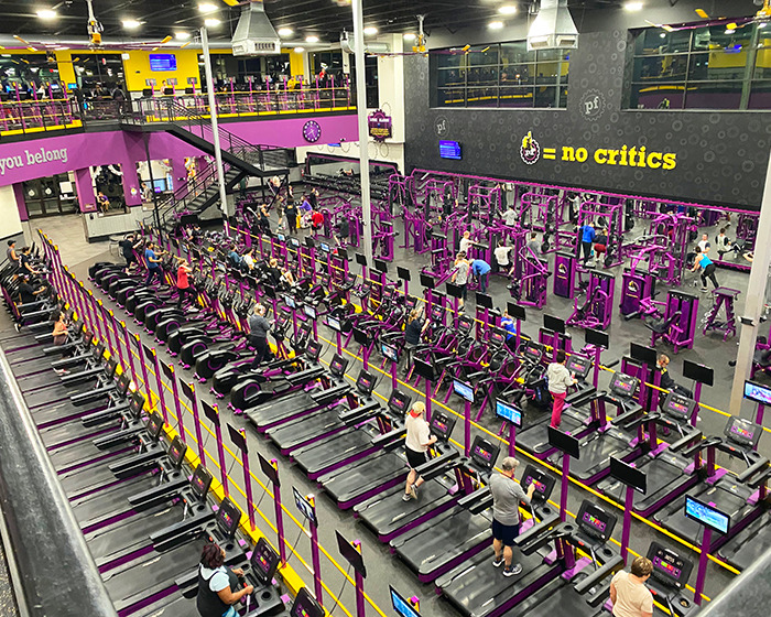 Busy Planet Fitness gym interior showing cardio and weight equipment, related to transphobic locker room policies debate. Busy Planet Fitness gym interior showing cardio and weight equipment, related to transphobic locker room policies debate.