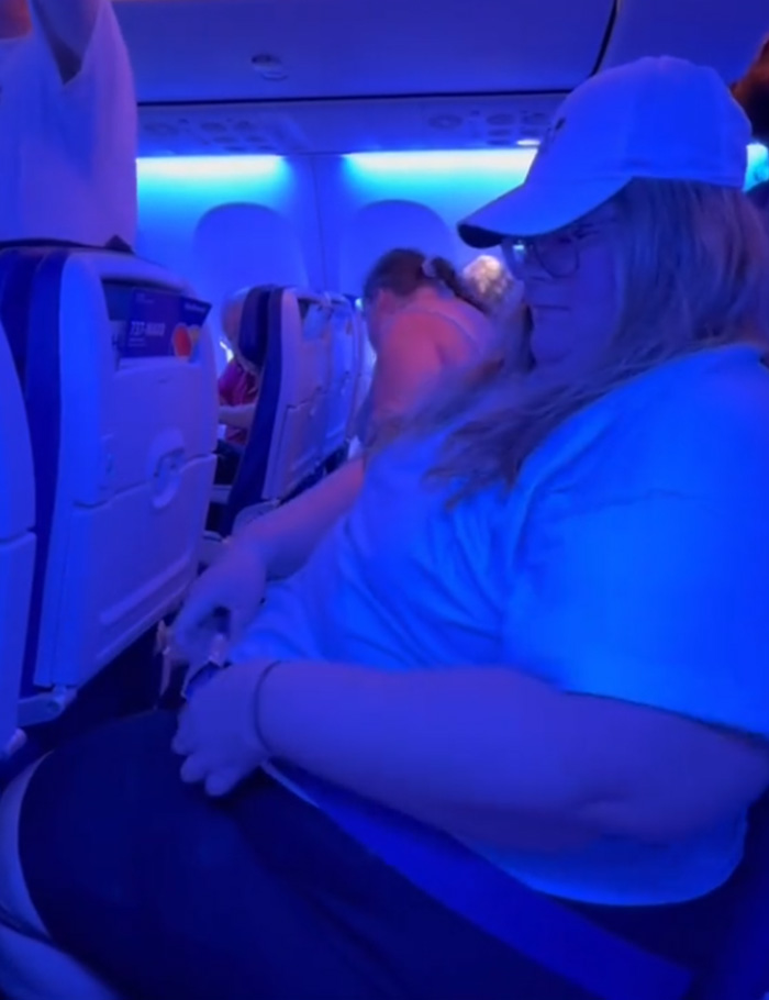 Plus size passenger seated on an airplane, highlighting concerns over new Southwest Airlines seating rules and passenger comfort.