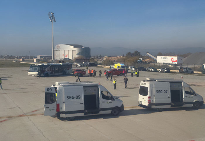 Airport scene with security vans and personnel responding after fighter jets scrambled over passenger's WiFi hotspot name incident.