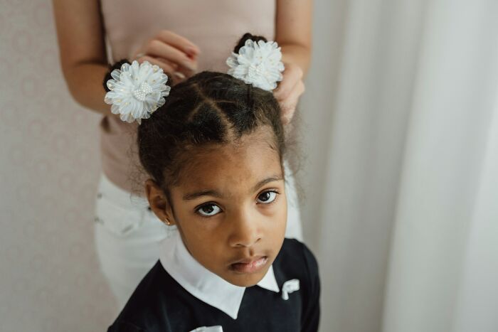 Young girl with hair styled in buns, wearing black dress, illustrating wedding moments that turned out to be accurate.
