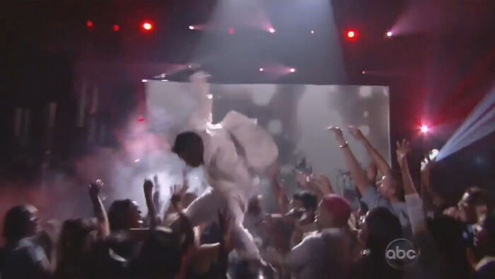 Performer crowd surfing at a live concert with audience reaching out during a pop culture moment that made people cringe hard.