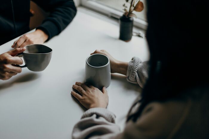 Two people holding coffee mugs at a table, illustrating everyday life cheat codes for making tasks easier.