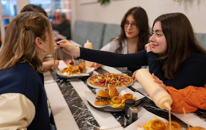 Three young professionals sharing a meal, highlighting what the general public doesn’t know about their jobs.