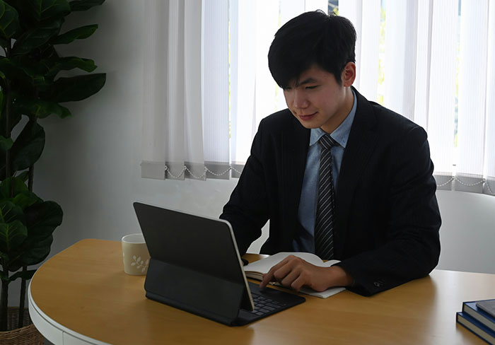 Young professional man in suit working on tablet and notebook, illustrating insights from professionals about their jobs.