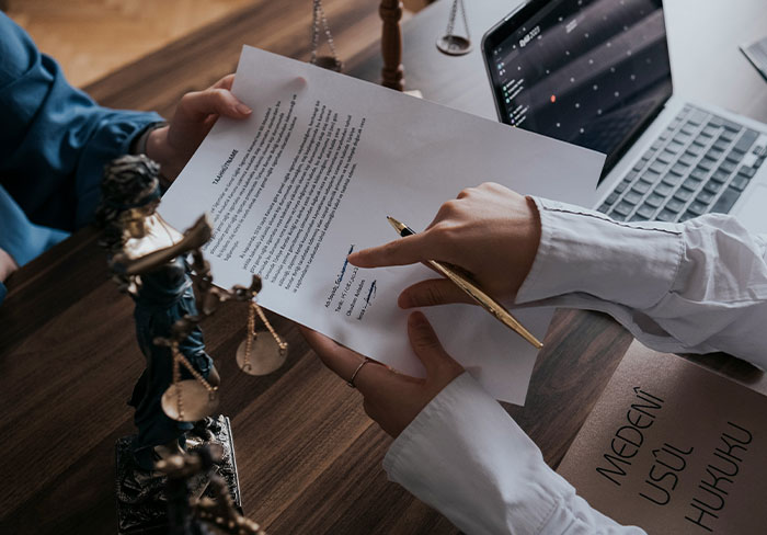 Two professionals reviewing and signing a legal document with scales of justice nearby, highlighting insights from professionals.