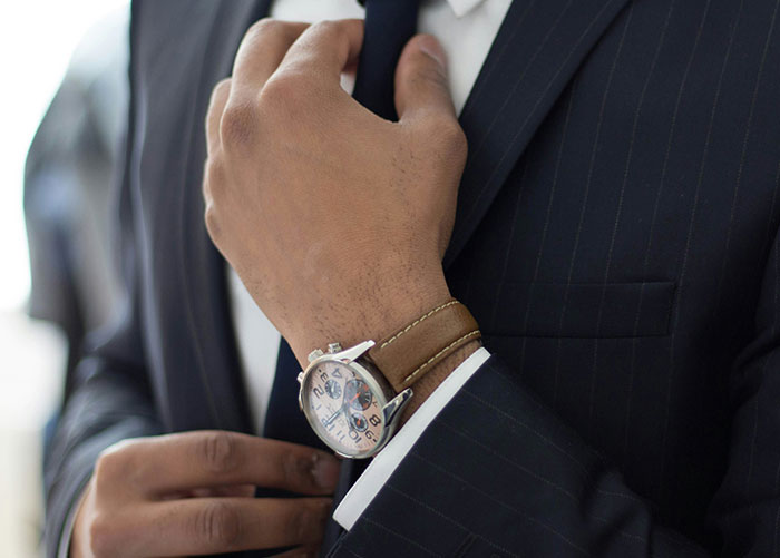 Professional in a dark suit adjusting tie, highlighting details unknown to the general public about their jobs.