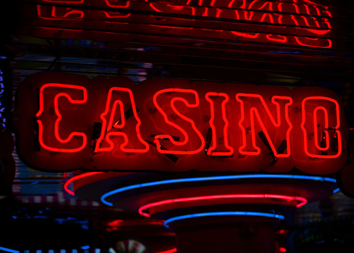 Red neon casino sign glowing at night with blue and red circular neon lights underneath, highlighting professionals' insights.