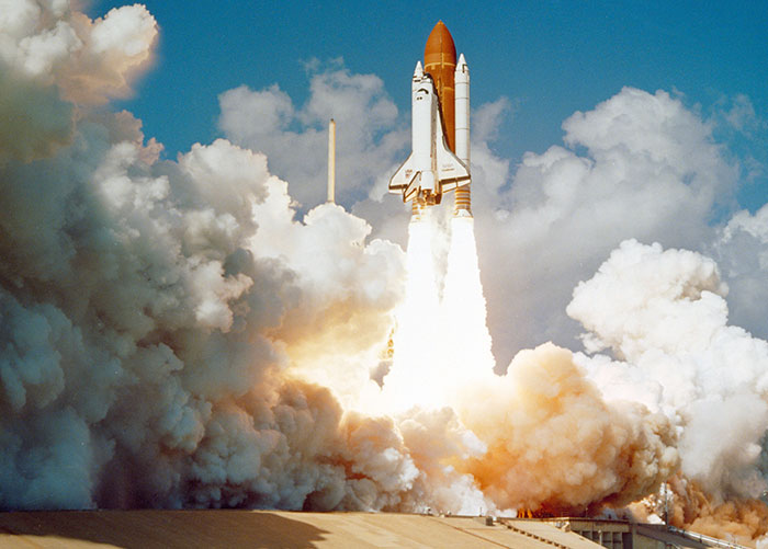 Space shuttle launching with powerful rockets and smoke, illustrating what professionals want the general public to know about their jobs.