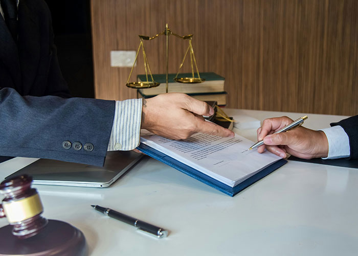 Two professionals discussing and signing legal documents with scales of justice and gavel on the desk representing professional jobs insights