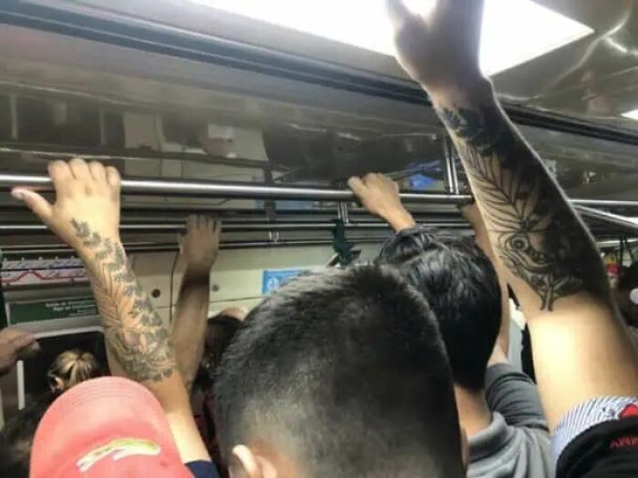 Packed subway car with tattooed arms gripping bars, passengers crammed together — glitches in the matrix scene