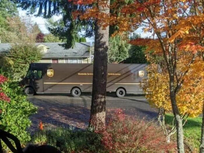UPS delivery truck appearing duplicated on a suburban street amid autumn trees, glitches in the matrix scene