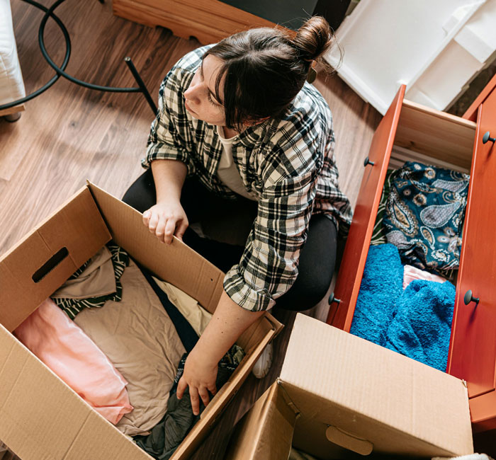 Woman packing and rearranging furniture and clothes in boxes, representing a long game played between MIL and DIL conflict.