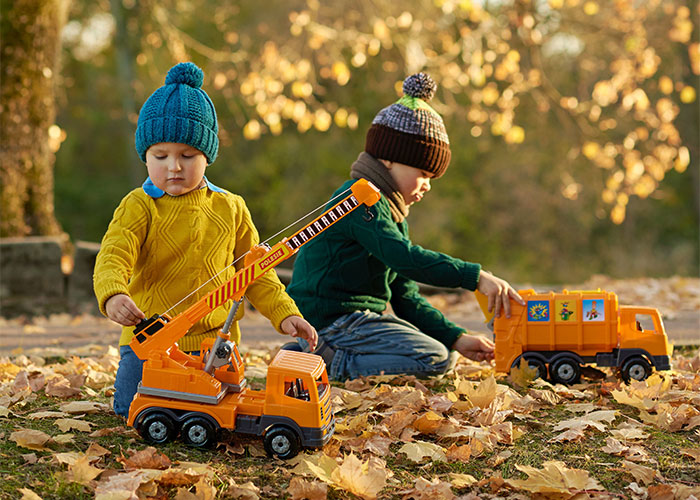 Two children playing with toy trucks outdoors in autumn, illustrating woman in labor upset over neighbor refusing kids at 3am.