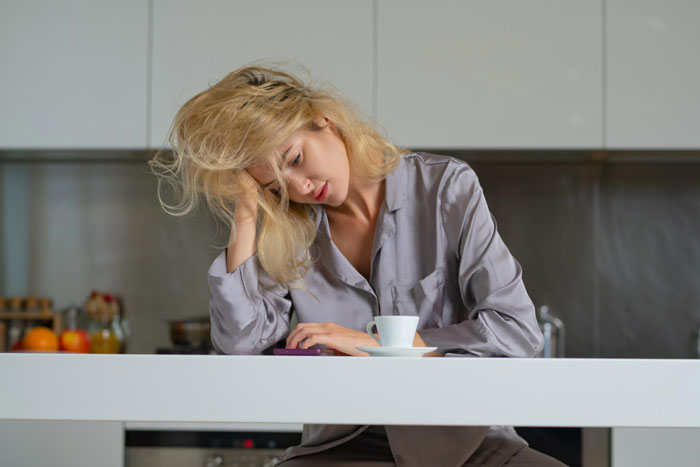 Woman looking tired and stressed in kitchen, reflecting wife breaking back acting like a housemaid as per hubs' demands.