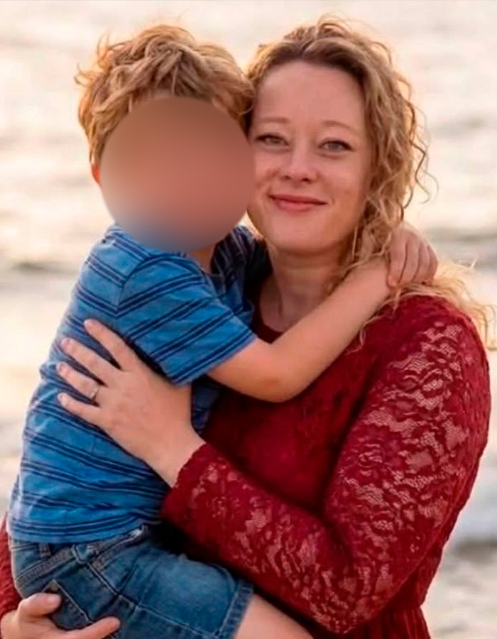 Woman in a red lace dress holding child by the ocean, related to autopsy released by Renee Good&rsquo;s family details.