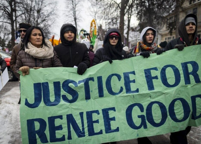 Group of protesters holding a justice for Renee Good banner during a cold weather demonstration.
