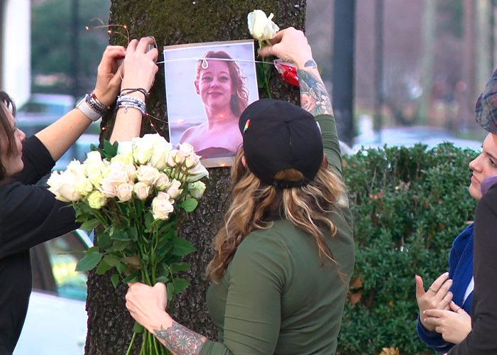 People placing flowers and a photo on a tree during a vigil for Renee Good&rsquo;s wife after fatal ICE incident.