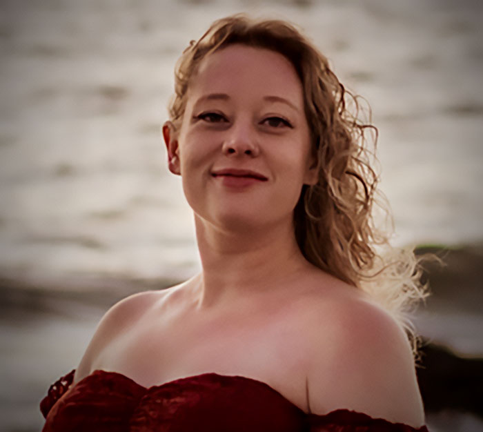 Woman with curly hair smiling warmly by the water, representing Minneapolis ICE agent crowdfunding hero story. Woman with curly hair smiling warmly by the water, representing Minneapolis ICE agent crowdfunding hero story.