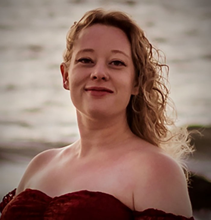 Woman identified as mom of a 6-year-old, slain by ICE, posing outdoors with a blurred water background.