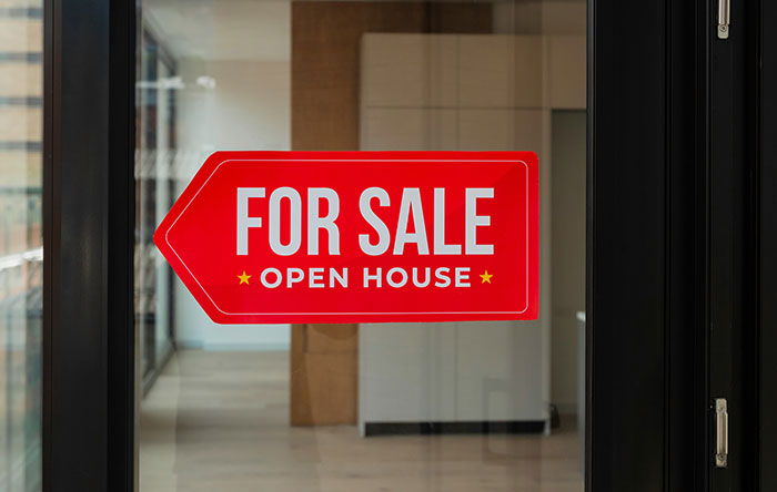 Red For Sale open house sign stuck on glass door of modern empty property, symbolizing last laugh revenge in real estate.