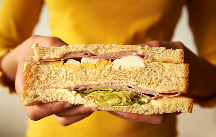 Person holding a homemade sandwich close-up, illustrating a moment of people getting the last laugh with glorious revenge.