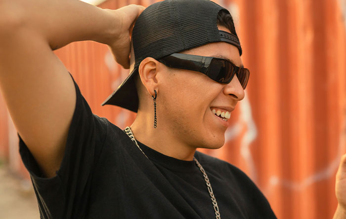 Young man wearing black cap and sunglasses smiling confidently, capturing the spirit of glorious revenge moments.